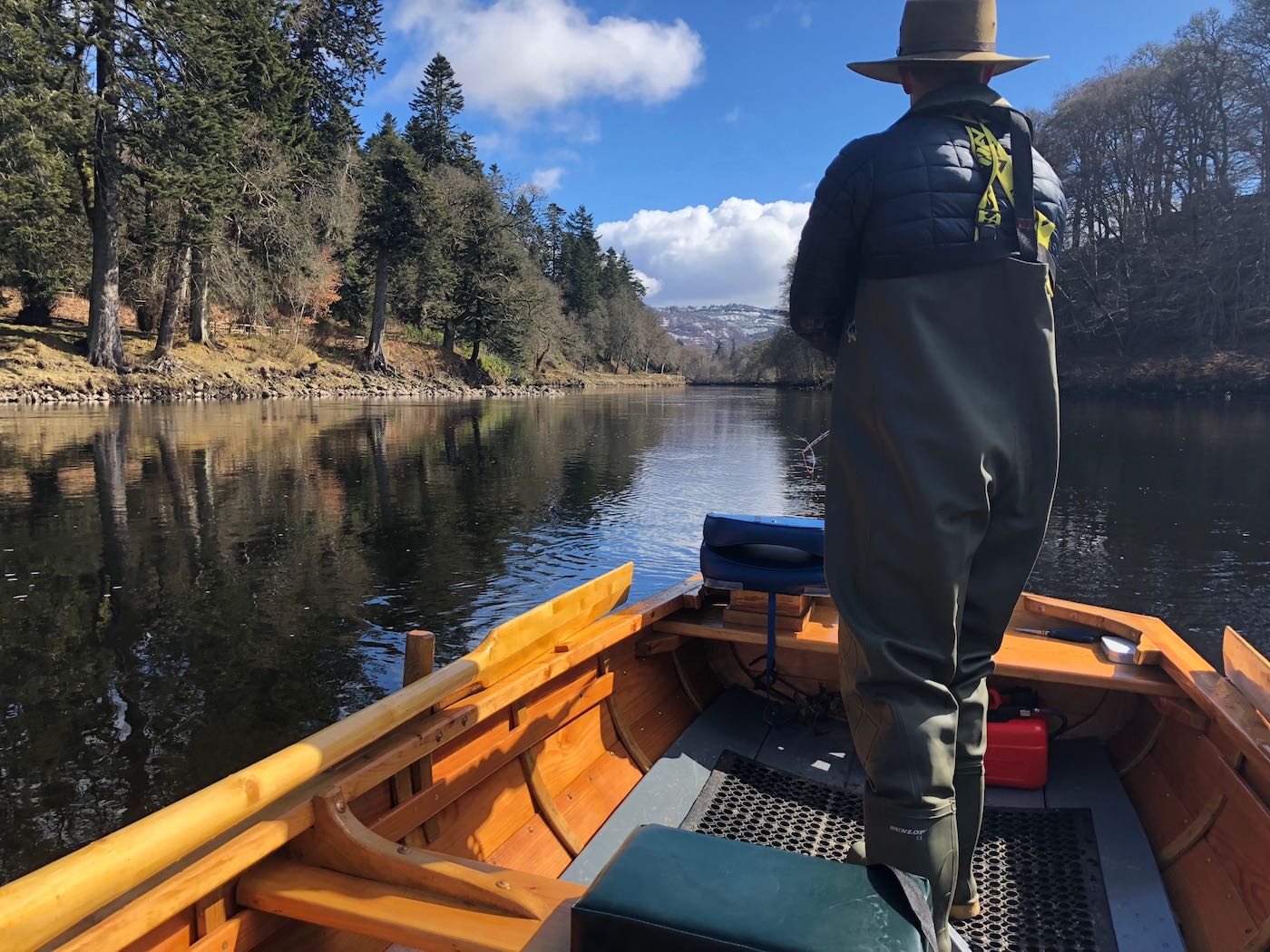 The River Tay boats offer a fishing advantage as they allow the salmon fishing holiday guests to cover distant salmon lies much more effectively. This salmon fisher was photographed on the Tay during Springtime on a nice bright settled fishing day.