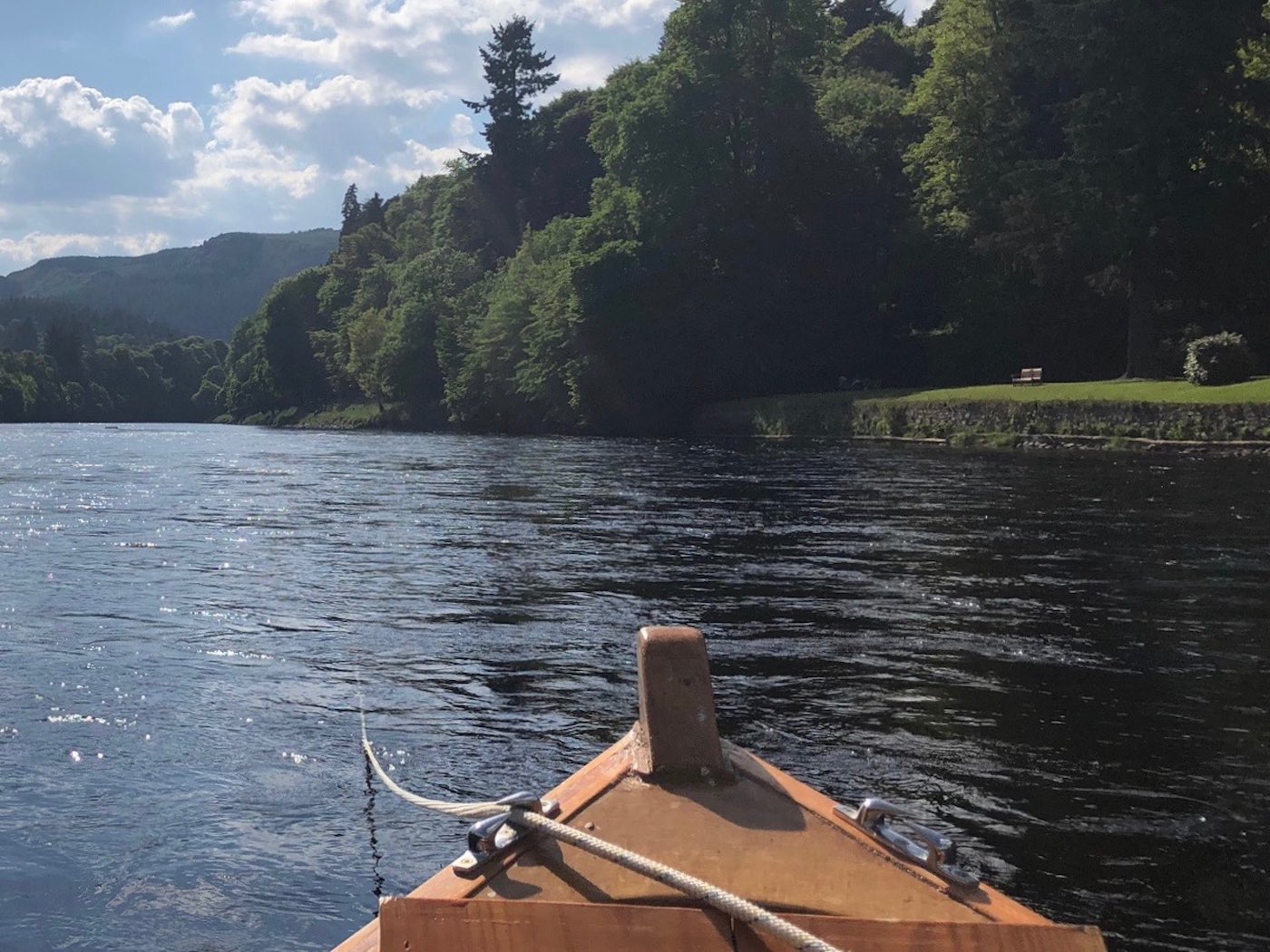 Here's a traditional River Tay 'coble' boat working off a long rope which allows a boat fisher to cover the salmon lies as the boatman slowing releases a yard of rope between each cast. This is a traditional boat fishing tactic on the larger Scottish salmon rivers and is a highly effective method for catching salmon. In the background you can see the lawn of the Dunkeld Cathedral grounds in Dunkeld.