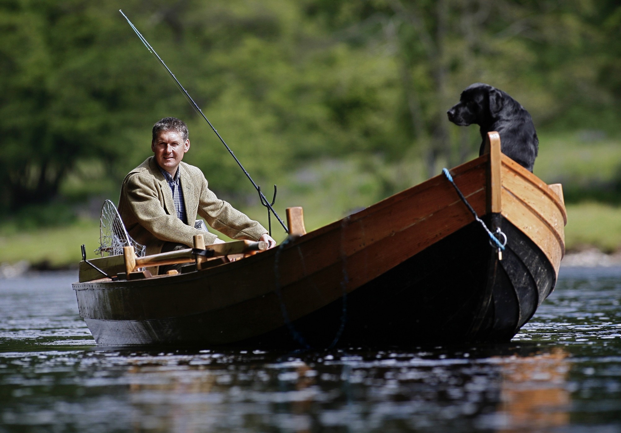 Here's Jock Monteith photographed with his black labrador dog 'Selkie' in the Cottar Pool of the Newtyle Beat during late Spring. This shot was taken by professional Scottish photographer Peter Sandground while Jock was in his tweed jacket and traditional River Tay salmon fishing boat near Dunkeld. You can almost make out the bluebells on the grassy slopes in the background.