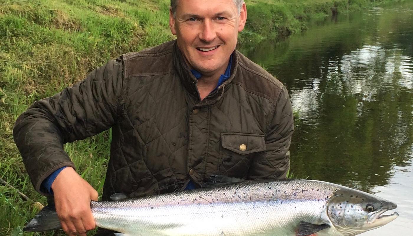 Jock Monteith is a well known professional salmon fishing tour organiser in Scotland and leading professional salmon fishing guide. Jock is holding a perfect fresh run 14lbs Summer salmon in this shot at the Daffodil Lie Pool of the River Tay's Kinnaird Beat which he hooked after a few casts while testing out a salmon fishing trip client's new fly rod .