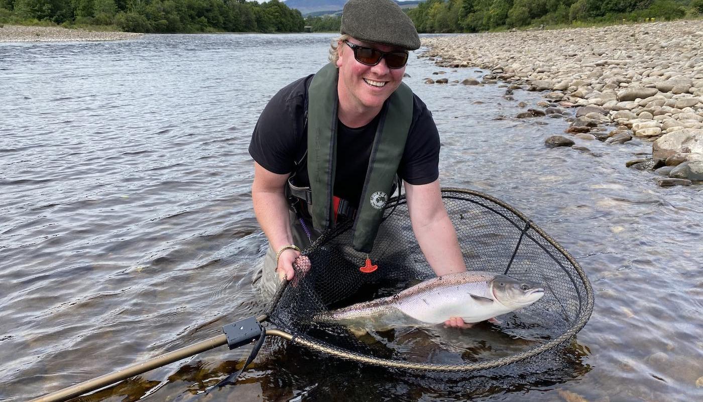 Look at the smile on this salmon angler's face moments after landing this perfect Summer salmon from the River Tay in Perthshire. Catching a salmon like this on the fly takes skill, patience and a good tactical understanding of how to fish your fly effectively. This 14lbs Summer salmon is being held in the McLean landing net for this photo before being released.